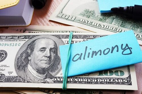 Hundred dollar bills on a table with a note that says "alimony"